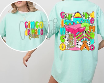 May include: A light blue t-shirt with the text "Cinco de Mayo Fiesta" on the front and a colourful graphic of a margarita glass, sombrero, and maracas on the back.