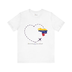 May include: White t-shirt featuring a heart-shaped dotted line with a Venezuelan flag graphic and a small airplane. The text "Lleva tu luz y tu aroma en mi piel" is printed below the heart.