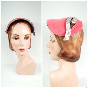 May include: A vintage pink hat with a curved brim and a decorative fabric band. The hat is displayed on a mannequin head. The hat's interior trim features a patterned fabric.