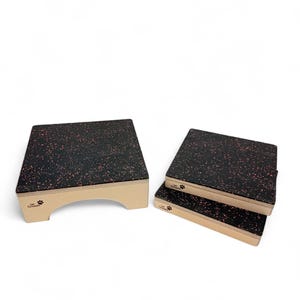 Pode incluir: Um conjunto de plataformas para tosquia de animais de estimação. As plataformas têm uma superfície preta com manchas vermelhas e uma moldura bege clara. Uma plataforma tem uma base arqueada, as outras estão empilhadas. O nome da marca e o logótipo da pata são visíveis.