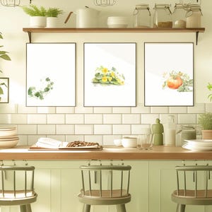 以下が含まれることがあります： 3つの額入り植物画が特徴のキッチンインテリア。黒いフレームに入ったプリントは、植物や花の水彩イラストです。キッチンには木製のカウンタートップ、白いタイルのバックスプラッシュ、緑色のスツールがあります。