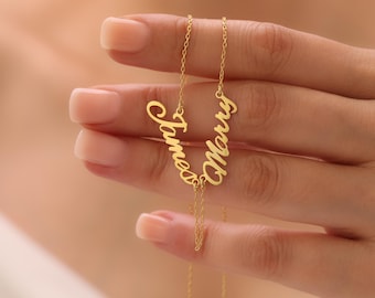 May include: A gold-colored necklace with the names "James" and "Marry" in a cursive font. The necklace is held by a person. The chain is delicate and the names are connected.