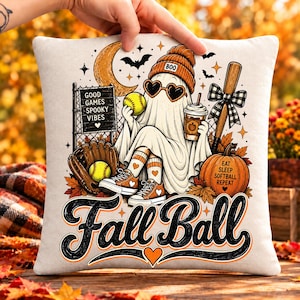 May include: A square throw pillow featuring a graphic of a ghost wearing a beanie, heart-shaped sunglasses, and sneakers, holding a softball and a coffee cup. The design includes a baseball bat, a glove, a pumpkin, and the text Fall Ball.