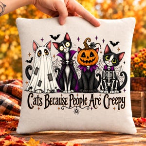 May include: A square off-white throw pillow featuring a graphic of four cats in Halloween costumes: a ghost, a vampire, a pumpkin-headed cat, and a skeleton. The text below reads, Cats Because People Are Creepy, with small spider and bat accents.