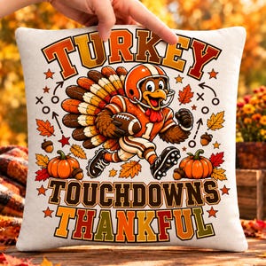 May include: A square throw pillow featuring a cartoon turkey wearing a football helmet and jersey, holding a football. The design includes orange pumpkins, autumn leaves, acorns, and the text TURKEY TOUCHDOWNS THANKFUL in bold letters.