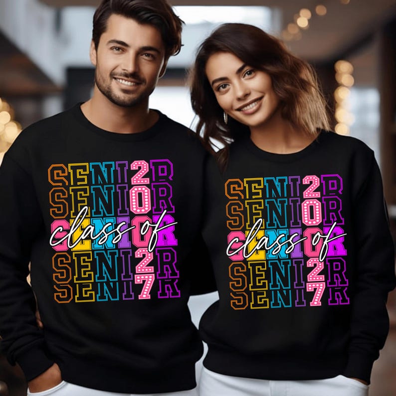 May include: Black sweatshirts featuring the text "SENIOR 2023" in vibrant, stacked block letters, with "class of" in cursive. The sweatshirts are worn by two people.
