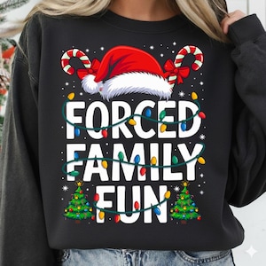 May include: Black sweatshirt with the text "FORCED FAMILY FUN" in white. The design includes a Santa hat, candy canes, Christmas lights, and two small Christmas trees. A festive holiday-themed design.