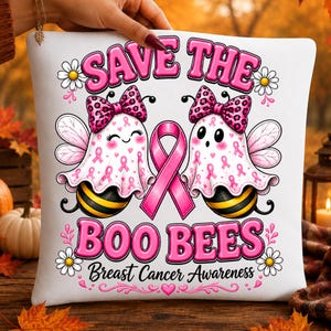 May include: A white square pillow featuring a graphic of two ghost-like bees wearing pink leopard print bows. Between them is a pink awareness ribbon. The text reads SAVE THE BOO BEES and Breast Cancer Awareness, surrounded by small daisies.