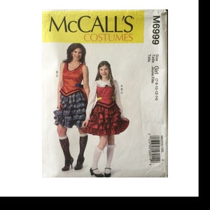 May include: McCall's Costumes sewing pattern for a girl's costume. The pattern is for sizes 7-8, 10, 12, and 14. The pattern includes a red and black plaid skirt, a red bodice with a yellow trim, and a white blouse with a Peter Pan collar.