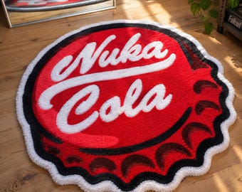 May include: A circular tufted rug shaped like a bottle cap, featuring a vibrant red background with the white text Nuka Cola written in a script font. The edges are scalloped with black and white detailing, mimicking the look of a metal cap.