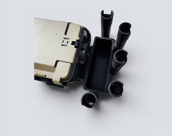May include: A tan rectangular storage box featuring a black plastic attachment with a rectangular compartment and five cylindrical rod holders extending outward. The storage unit has a secure latch mechanism on the top surface and a sturdy build.