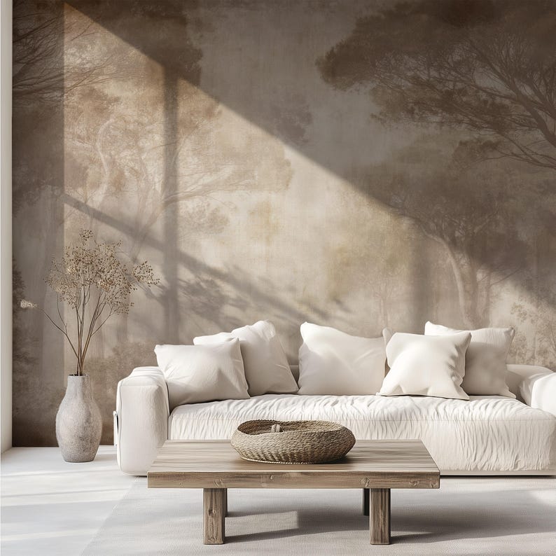 Puede incluir: Escena de sal&oacute;n con un sof&aacute; blanco, cojines blancos, una mesa de centro de madera y una cesta tejida. El fondo es un mural que representa una escena de bosque con un rayo de luz.