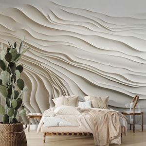 Puede incluir: Un dormitorio con una paleta de colores neutros. El punto focal es una pared texturizada en forma de ola en tonos beige y blanco. Una cama con ropa de cama y almohadas beige está en primer plano, con un cactus en una cesta de mimbre a la izquierda.
