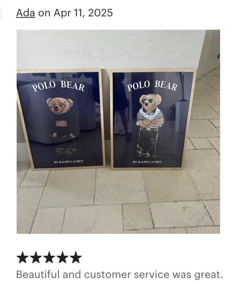 Puede incluir: Dos impresiones enmarcadas con el oso Polo. Cada impresi&oacute;n tiene un fondo azul marino con las palabras "POLO BEAR" en blanco. Un oso lleva un su&eacute;ter con una bandera estadounidense, el otro lleva una camisa a rayas. "BY RALPH LAUREN" est&aacute; impreso debajo.