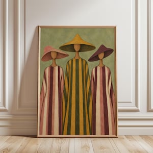 May include: A framed wall art print featuring three stylized figures wearing wide-brimmed hats and long, striped robes. The central figure wears a yellow hat and a yellow and green striped robe, flanked by two figures in pink and purple hats.