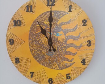 Puede incluir: Un reloj redondo amarillo con un diseño de sol y luna. La esfera del reloj tiene números negros del 1 al 12 y agujas de hora y minuto negras. El sol es amarillo con una cara marrón y un ojo azul. La luna es marrón con un patrón blanco y negro.
