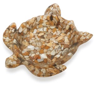 May include: A decorative turtle-shaped dish made of small, colorful pebbles. The dish features a shallow bowl and four flipper-like extensions. The pebbles are in shades of beige, brown, and white, creating a textured surface.
