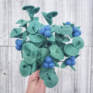 May include: A felt eucalyptus stem with blue felt berries. The stem is green and has a realistic look.