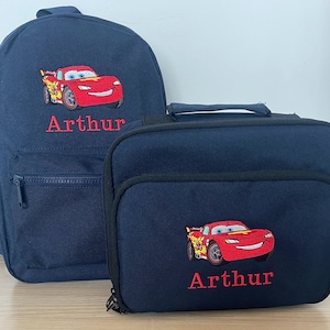 Puede incluir: Un conjunto de mochila y bolsa de almuerzo azul con una imagen bordada de Rayo McQueen de Cars y el nombre "Arthur".