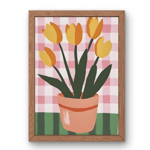 Könnte beinhalten: Gerahmter Kunstdruck mit einem Topfarrangement von Tulpen. Die Tulpen sind gelb und orange, mit grünen Stielen und Blättern, vor einem rosa-weiß karierten Hintergrund. Der Topf ist pfirsichfarben und der Rahmen ist holzfarben.