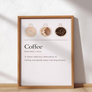 Könnte beinhalten: Ein gerahmter Druck mit einem hellen Holzrahmen. Der Druck zeigt das Wort "Coffee" mit einer Definition und dem Satz "Eine warme, köstliche Alternative, jeden Morgen für immer alle zu hassen." Über dem Text befinden sich drei Kaffeetassen-Illustrationen.