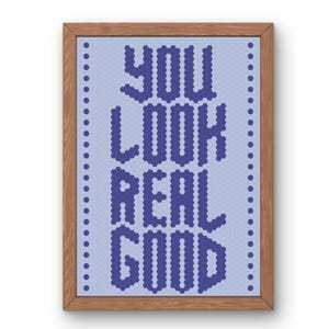 Könnte beinhalten: Ein gerahmtes Kreuzstich-Wandbild mit dem Text YOU LOOK REAL GOOD in dunkelblauen, pixeligen, sechseckigen Buchstaben auf hellblauem Hintergrund mit einem sich wiederholenden Sechseckmuster und einem vertikalen Rand aus dunkelblauen Sechsecken.