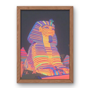 May include: A framed art print showcasing a vibrant, stylised representation of the Sphinx. The artwork uses bright colours like orange, blue, purple, and green for a striking effect. The print is enclosed in a natural wood frame.