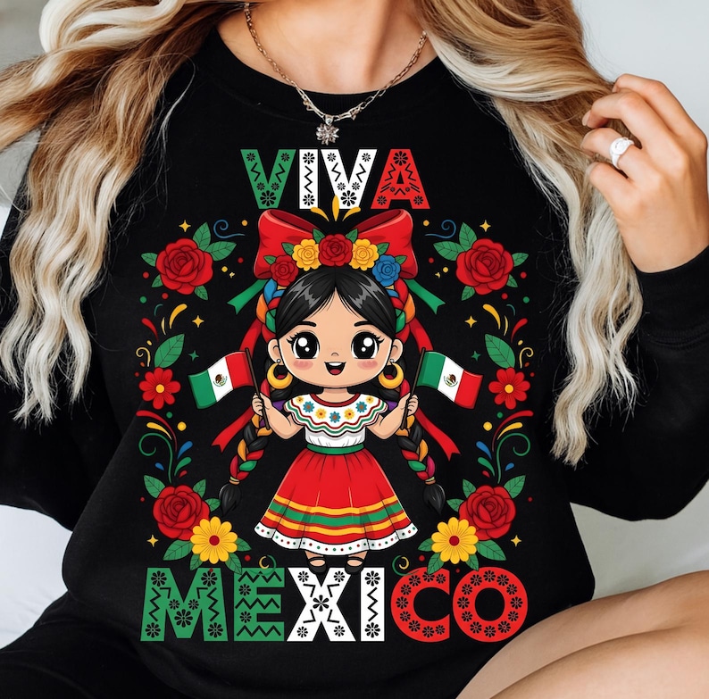 May include: Black sweatshirt featuring a cartoon girl in a traditional Mexican dress, holding Mexican flags. The design includes the words "VIVA MEXICO" in colorful lettering, surrounded by roses and floral accents. The girl has black braids and is wearing a flower crown.