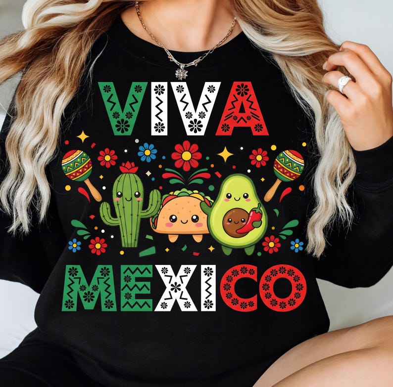 Op de afbeelding: Zwarte sweatshirt met de tekst "VIVA MEXICO" in groen, wit en rood. Het ontwerp bevat een cactus, een taco en een avocado met lachende gezichten, maracas en kleurrijke bloemen.