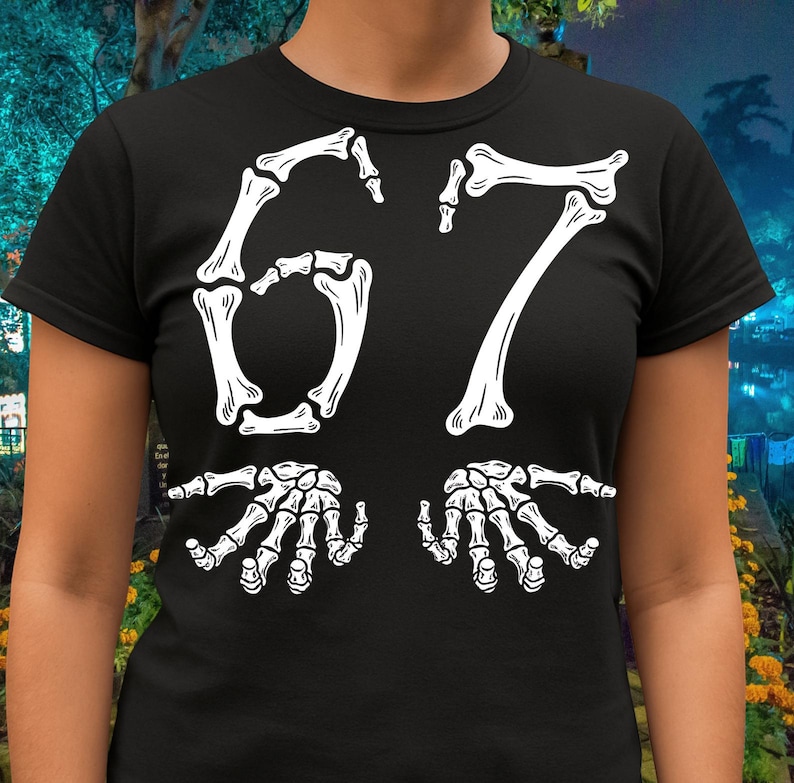 May include: Black t-shirt with a white skeleton-themed design. The design features the number "67" in a bone-like font, with two skeletal hands at the bottom. The shirt is a crew neck style.