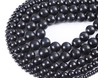 May include: A strand of black gemstone beads in various sizes. The beads are round and smooth, and they are arranged in a circular pattern. The beads are all black, and they have a glossy finish.