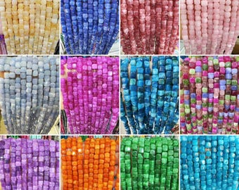 Peut inclure: Une collection de perles de pierres précieuses colorées dans diverses nuances, dont le jaune, le bleu, le rouge, le rose, le gris, le violet, le turquoise, l'orange, le vert et le sarcelle. Les perles sont de forme carrée et enfilées, idéales pour la création de bijoux.