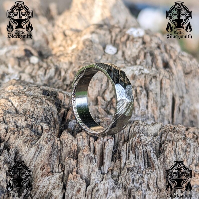 May include: A silver ring with a hammered finish and a unique, angular design. The ring is made of metal and has a polished surface.
