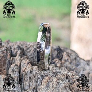 May include: A silver ring with a textured, patterned surface. The ring is made of metal and has a polished finish.