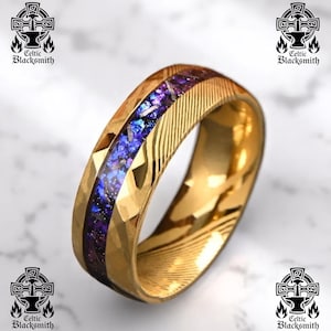 May include: A gold ring featuring a central inlay of shimmering purple and blue material. The ring has a textured surface with geometric and linear patterns. The Celtic Blacksmith logo is visible in the background.