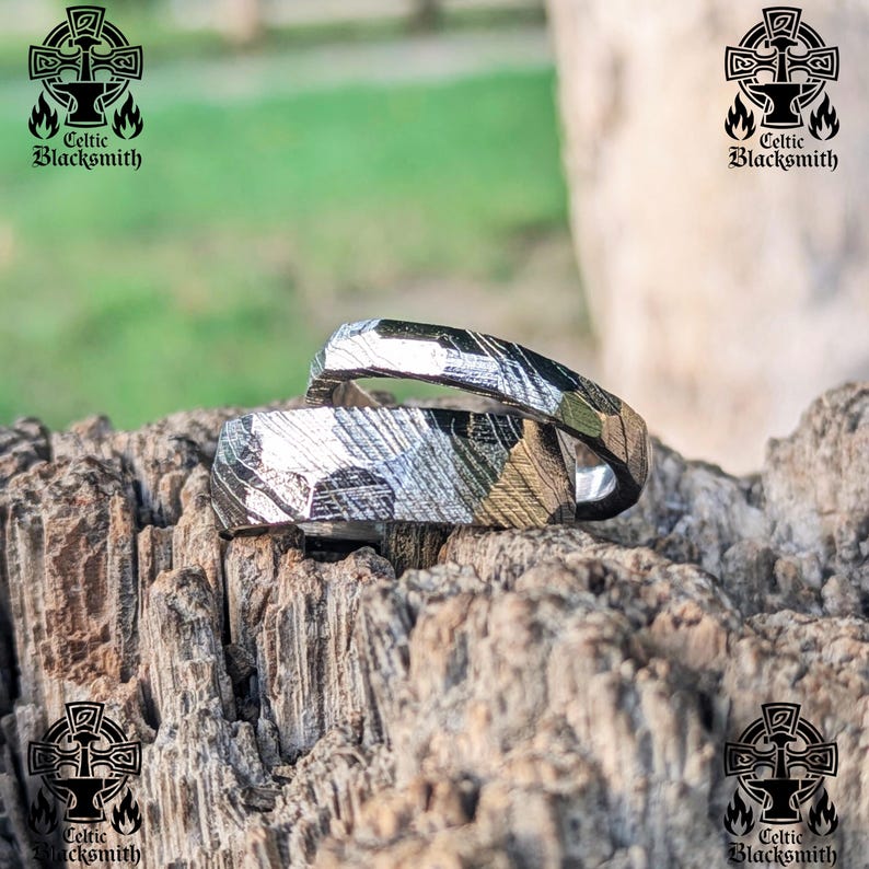 May include: Two silver rings with a hammered finish, intertwined and resting on a piece of weathered wood. The rings have a unique, textured pattern that resembles a swirling design. The rings are a symbol of love and commitment.