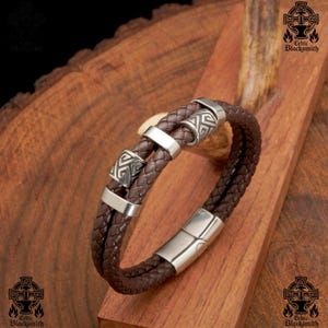 May include: A brown leather bracelet with a silver clasp and three silver beads with Celtic knot designs.