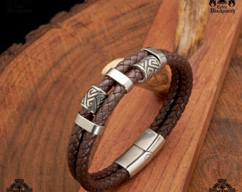 May include: A brown leather bracelet with a silver clasp and three silver beads with Celtic knot designs.
