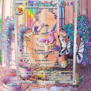 Peut inclure: Une carte à collectionner holographique Espeon représentant une créature rose de type psy assise dans une jardinière en pierre. La carte affiche 110 PV, les attaques Enchant et Solar Verdict, ainsi que des illustrations de papillons et fleurs.