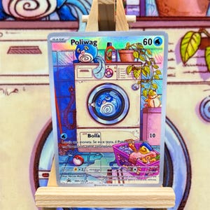 May include: A trading card depicting a cartoon Poliwhag character in a washing machine scene. The card is predominantly blue and white, with text and numbers. It's presented on a small wooden easel.