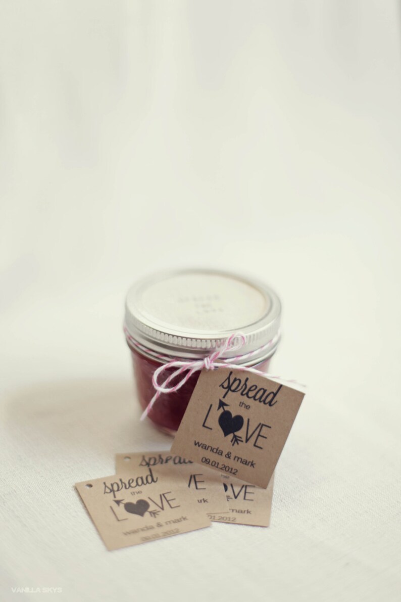 Puede incluir: Un peque&ntilde;o frasco de vidrio lleno de una sustancia roja, atado con un cordel blanco y rosa, y una etiqueta de papel marr&oacute;n que dice "Spread the LOVE wanda & mark 09.01.2012".