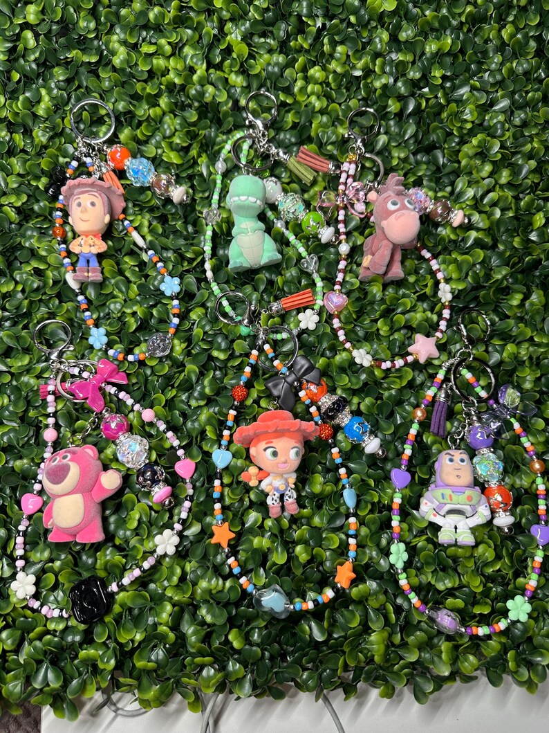K&ouml;nnte beinhalten: Eine Sammlung von Schl&uuml;sselanh&auml;ngern mit Charakteren aus dem Animationsfilm Toy Story. Jeder Schl&uuml;sselanh&auml;nger hat einen Charakteranh&auml;nger, bunte Perlen und einen Metallring. Zu den Charakteren geh&ouml;ren Woody, Rex, Bullseye, Lotso, Jessie und Buzz Lightyear.