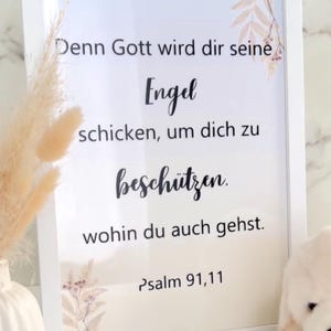 Könnte beinhalten: Weiß gerahmter Druck mit dem Text "Denn Gott wird dir seine Engel schicken, um dich zu beschützen. wohin du auch gehst. Psalm 91,11". Der Druck hat florale Akzente und befindet sich neben einer Vase mit getrockneten Blumen.