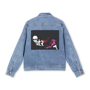 Könnte beinhalten: Eine hellblaue Jeansjacke mit einem rechteckigen schwarzen Aufnäher auf der Rückseite. Der Aufnäher zeigt eine weiße Totenkopfgrafik, die in abstrakte rote und violette Formen übergeht, sowie ein kleines weißes Knochensymbol unten rechts.