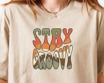 May include: A beige t-shirt with the text "STAY GROOVY" in a retro, colourful font.