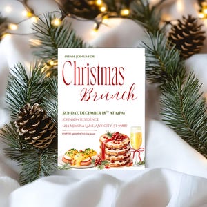 May include: A Christmas Brunch invitation with red script text on a white background. The invitation includes details for the event, along with watercolor illustrations of food and a glass of champagne. Pine needles and a pinecone decorate the edges.