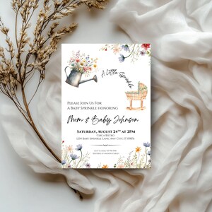 Peut inclure: Invitation pour une baby shower avec des illustrations &agrave; l'aquarelle. Comprend un arrosoir d&eacute;bordant de fleurs, un berceau et des motifs floraux. Le texte indique "A Little Sprinkle" et les d&eacute;tails de l'&eacute;v&eacute;nement.