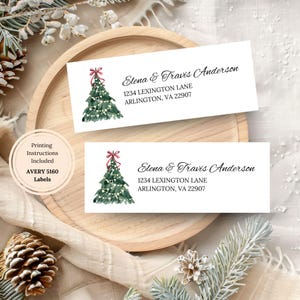 May include: Two white address labels with a watercolor Christmas tree design. The labels include the names "Elena & Travis Anderson" and address details. A circular label indicates "Printing Instructions Included".