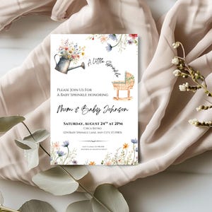 Peut inclure: Invitation pour une baby shower avec des illustrations &agrave; l'aquarelle. L'invitation pr&eacute;sente un arrosoir avec des fleurs, un berceau et le texte "A Little Sprinkle". L'invitation indique "Mom & Baby Johnson" et comprend les d&eacute;tails de l'&eacute;v&eacute;nement.