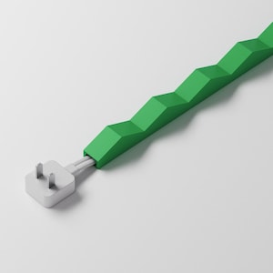 Puede incluir: Un protector de cable de color verde brillante con una estructura geométrica repetitiva en zigzag o tipo acordeón. El protector envuelve un cable eléctrico blanco que termina en un enchufe eléctrico blanco estándar de dos clavijas planas.
